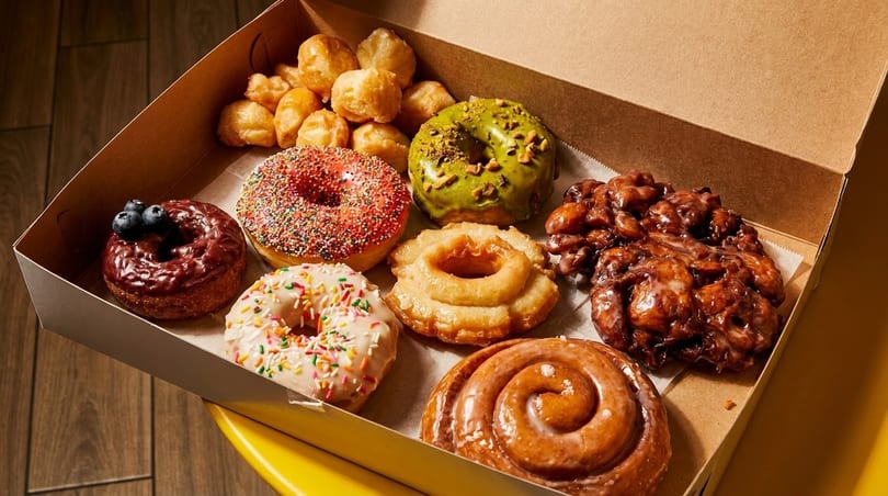 A box filled with an assortment of colorful donuts, including glazed, sprinkled, and blueberry-topped.